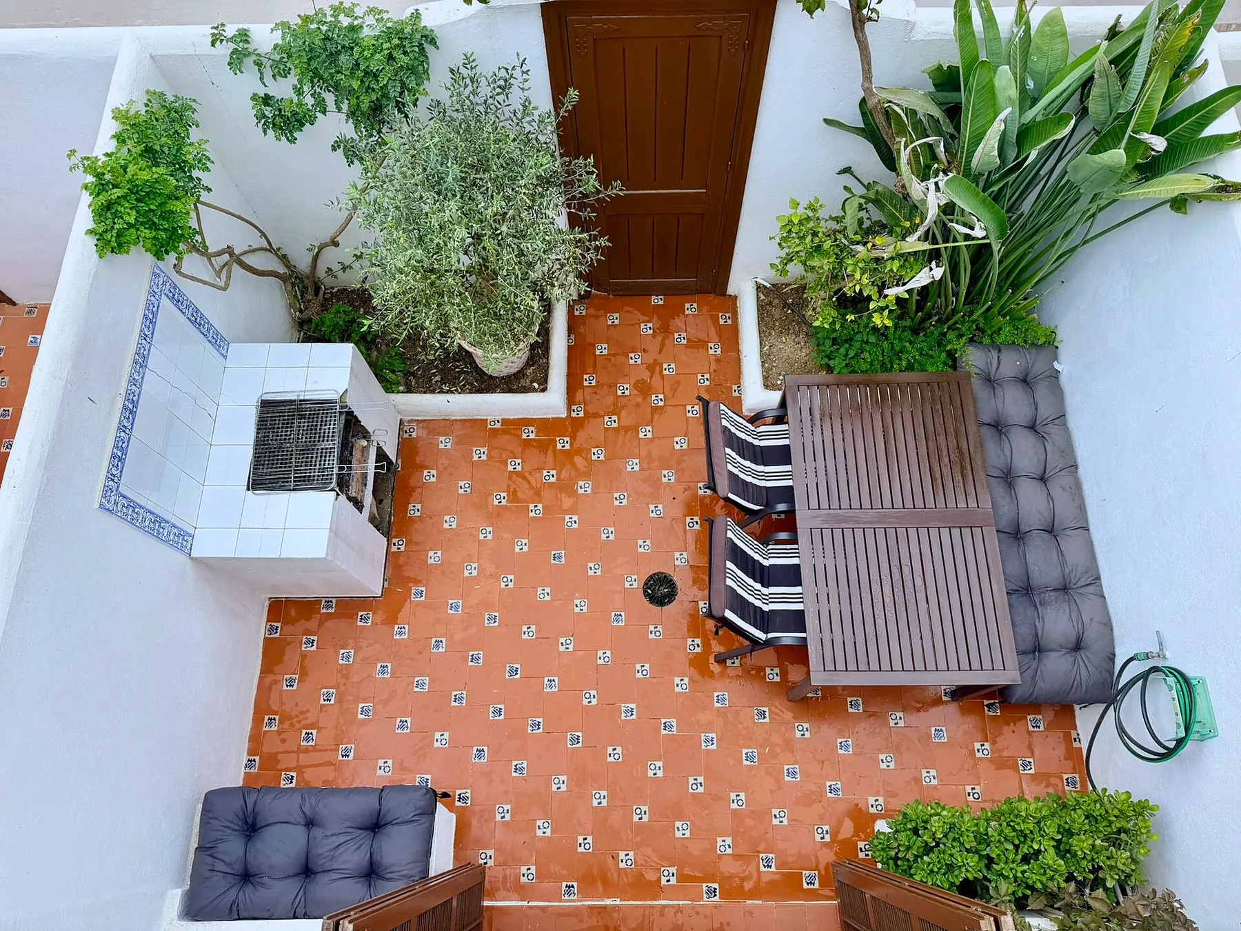 Courtyard seen from above with terracotta tiles, grill and lounge seating