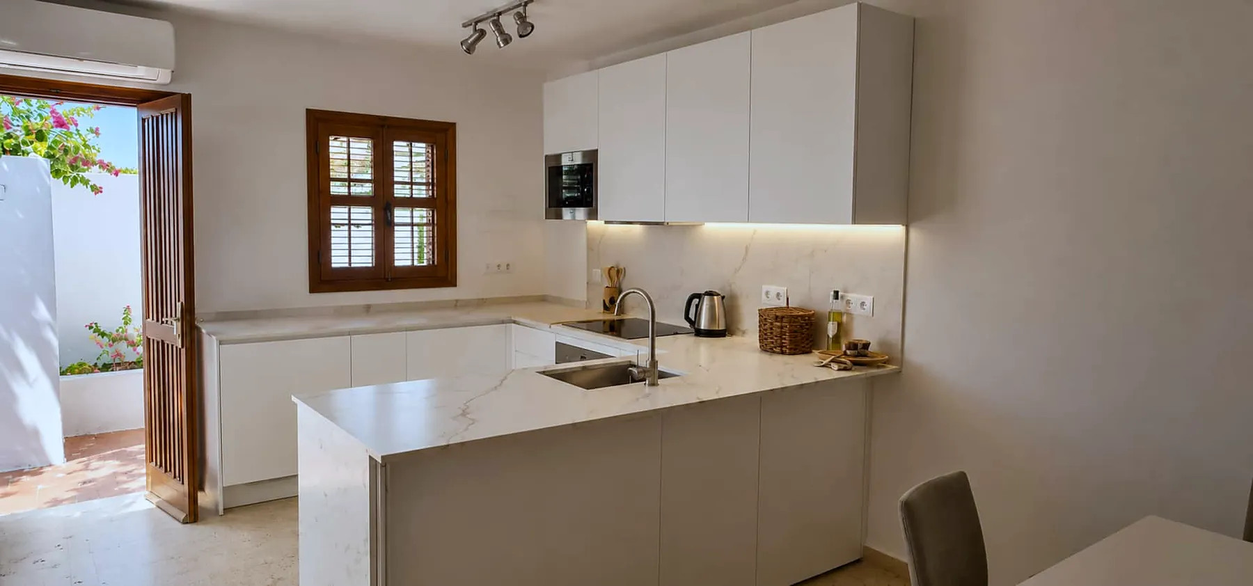 White kitchen with stone worktops and courtyard door