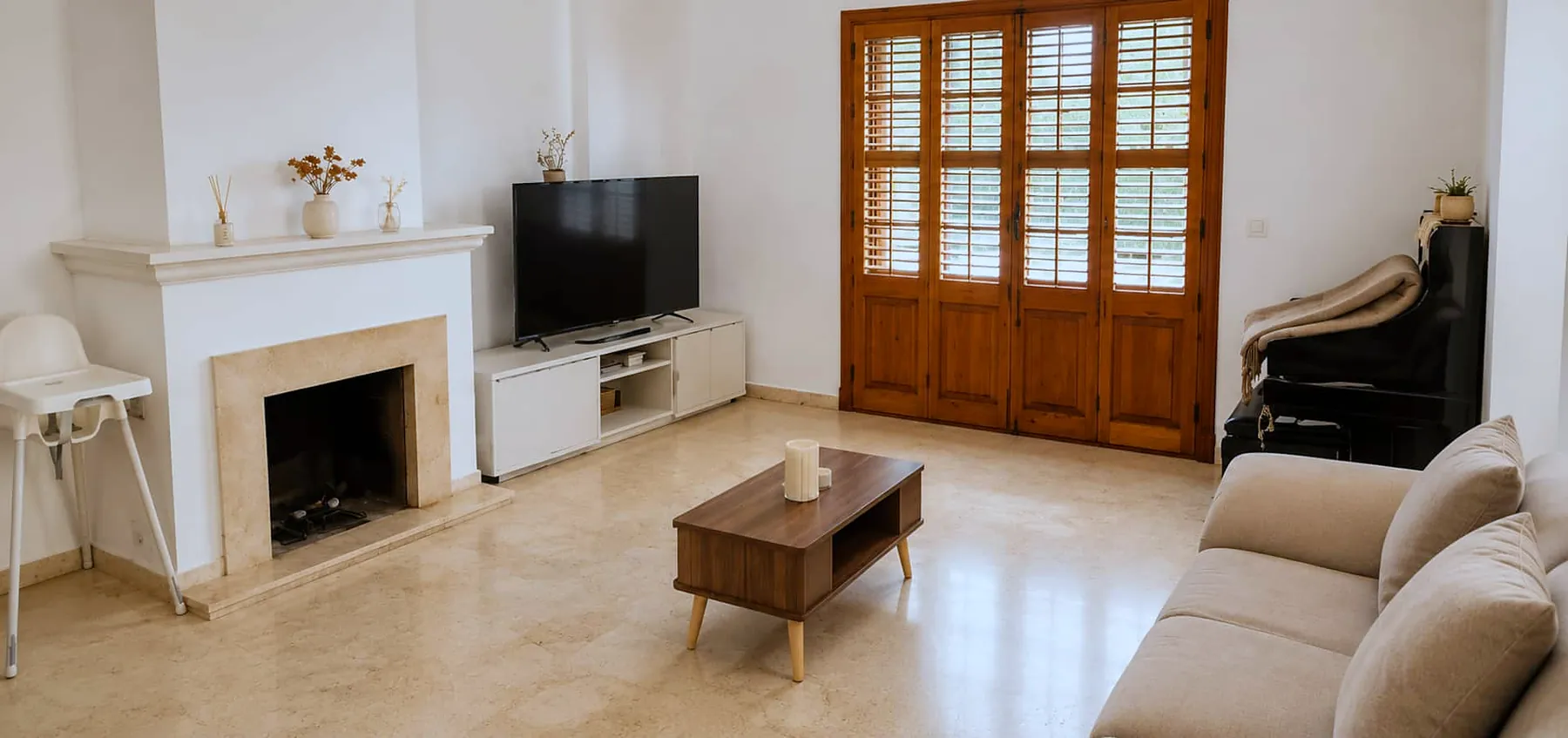 Living room with fireplace, TV and wooden shutters